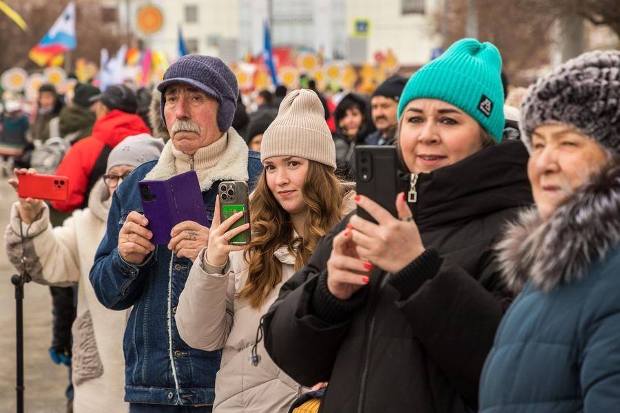 Townspeople watch the cheerful procession with curiosity