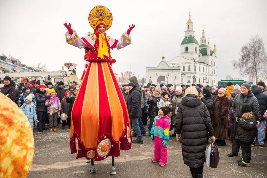 The crowd adores the stilt walkers, and they return the affection wholeheartedly
