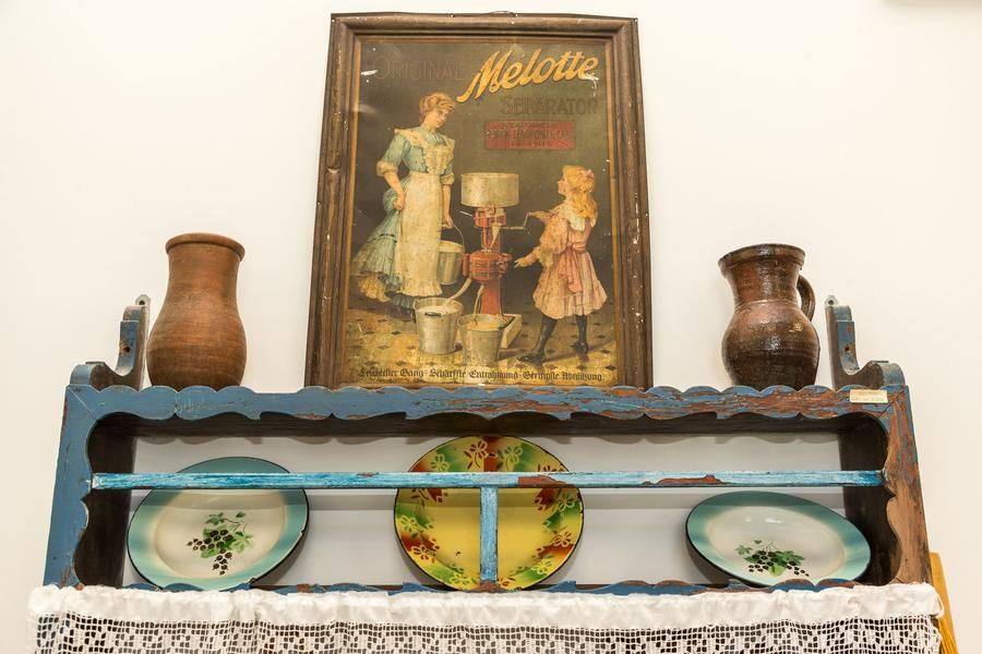 On the dish shelf are timeless items: simple enamel plates, clay milk vessels, and even an advertisement for a separator