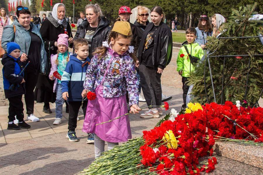 Omsk residents, young and old, lay flowers at the flame
