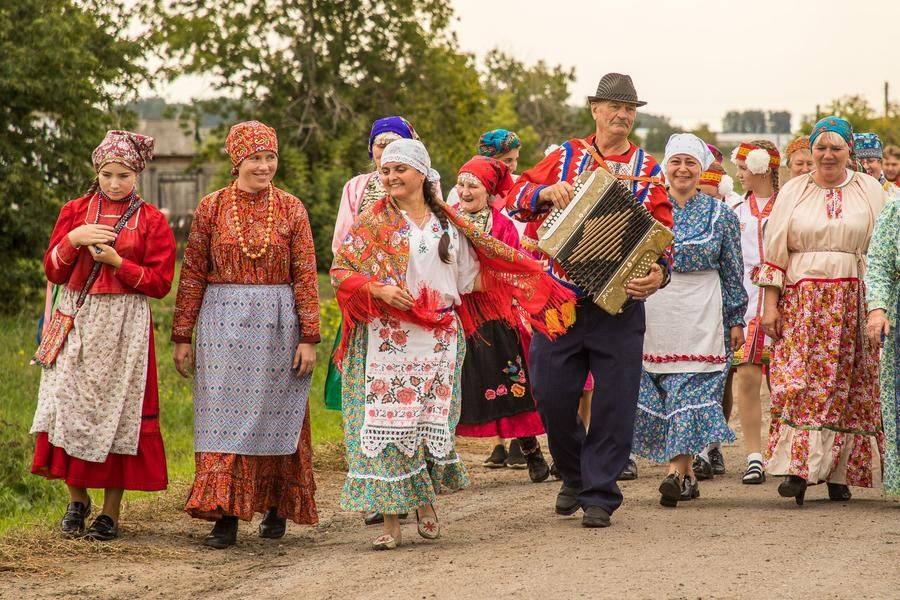 Leaving the historic house, the festival-goers walk in a column toward the festival meadow