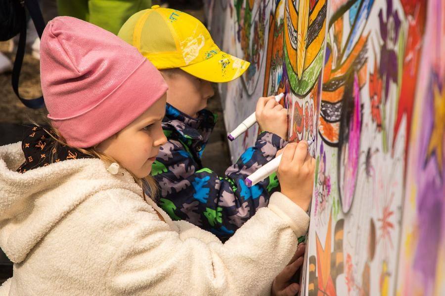 Next to it, children are enthusiastically colouring a big mural of the milestones of Victory