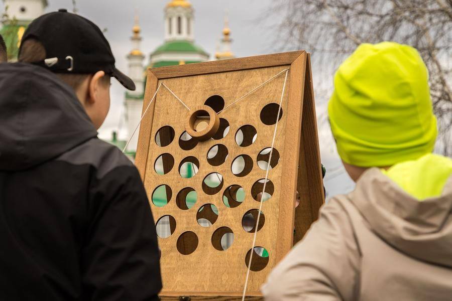 At one station, participants must lift a wooden disc using two strings
