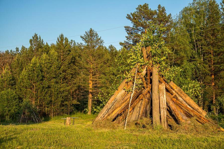 On a cozy meadow, the grass is mowed and huge bonfires are stacked