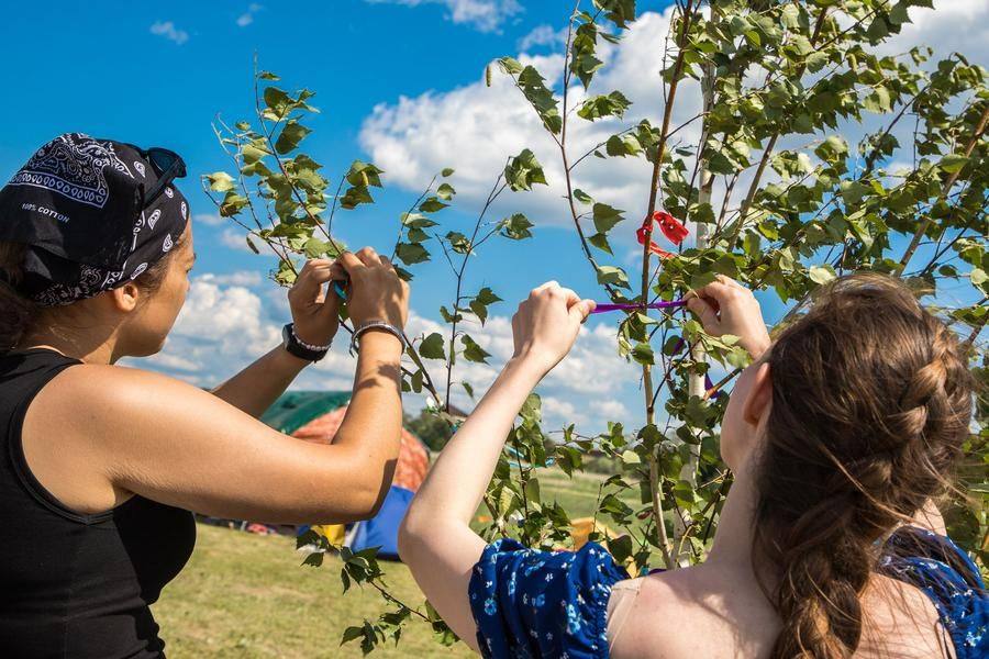 A young birch tree is decorated with ribbons, and everyone makes a wish