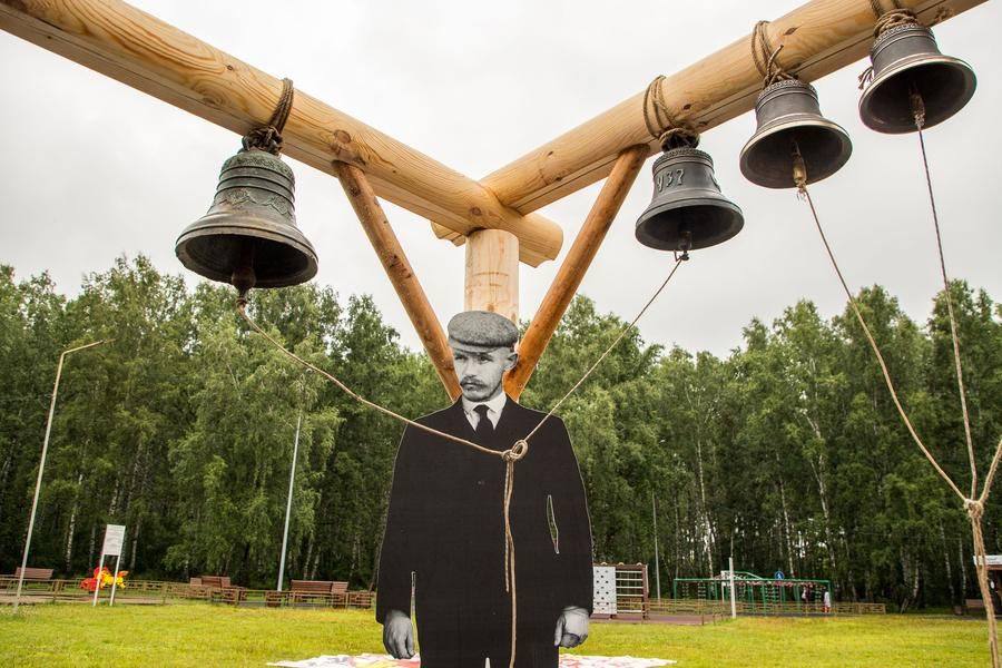 The belfry is decorated with life‑size photos of Tyumen merchants — a father and his two sons
