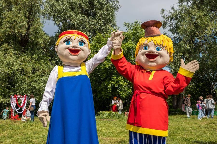 Friendly “villagers” invite everyone to a sun‑drenched glade where wreaths are being woven