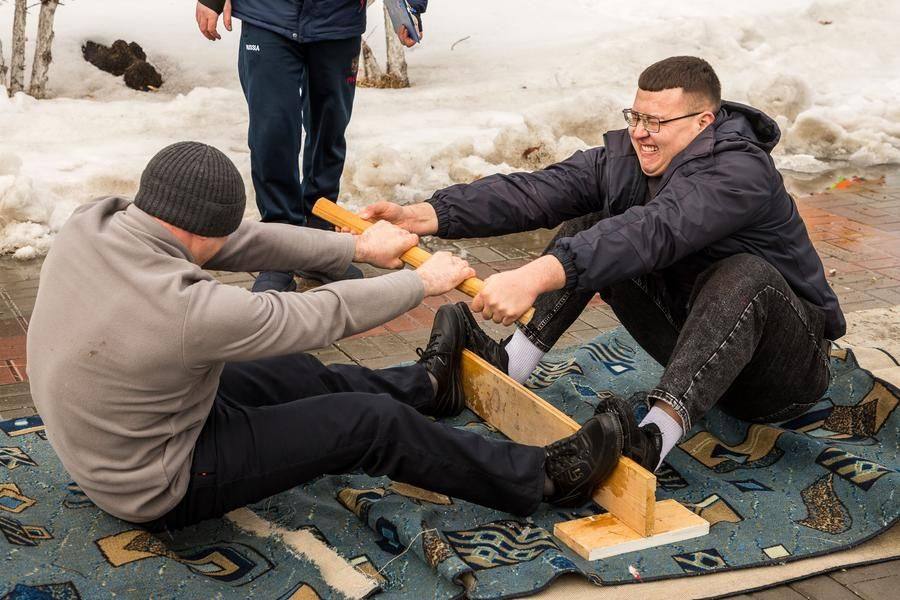 Opponents brace their feet against a board and pull on a wooden stick (the “mas”)